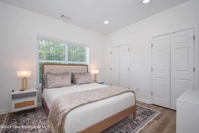 bedroom featuring baseboards, visible vents, wood finished floors, two closets, and recessed lighting