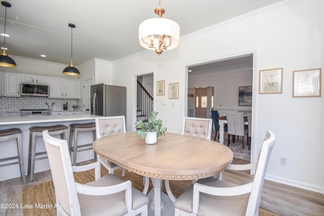 dining area with stairs, ornamental molding, and light wood-type flooring