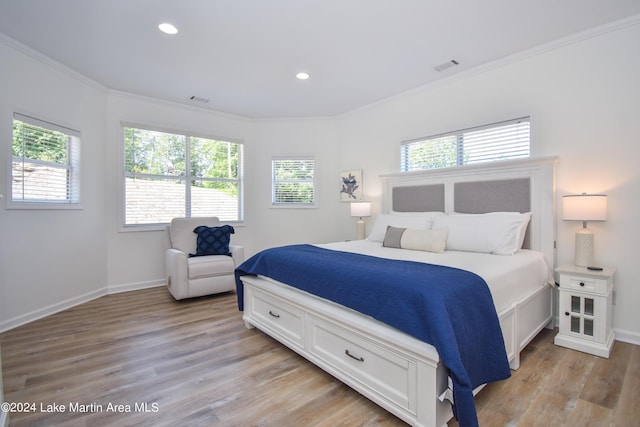 bedroom featuring baseboards, ornamental molding, visible vents, and light wood-style floors