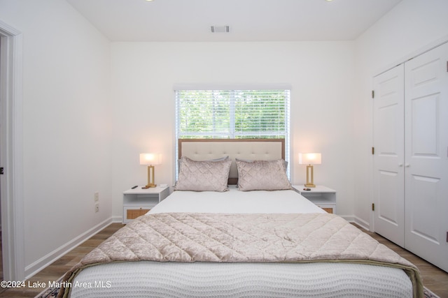 bedroom with baseboards, a closet, visible vents, and wood finished floors