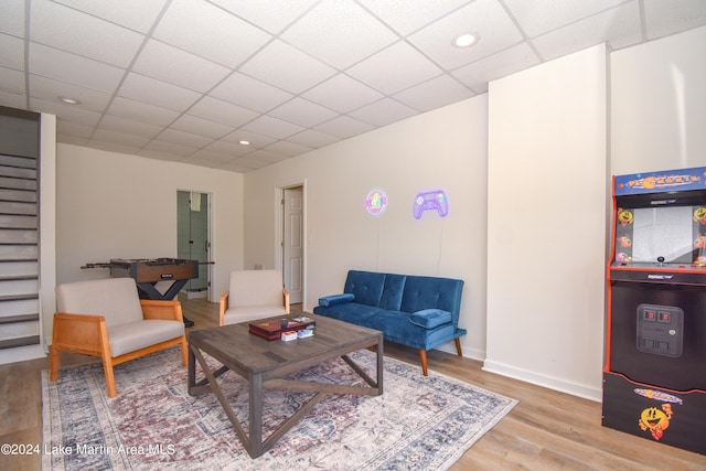 living area featuring a drop ceiling, recessed lighting, wood finished floors, baseboards, and stairs