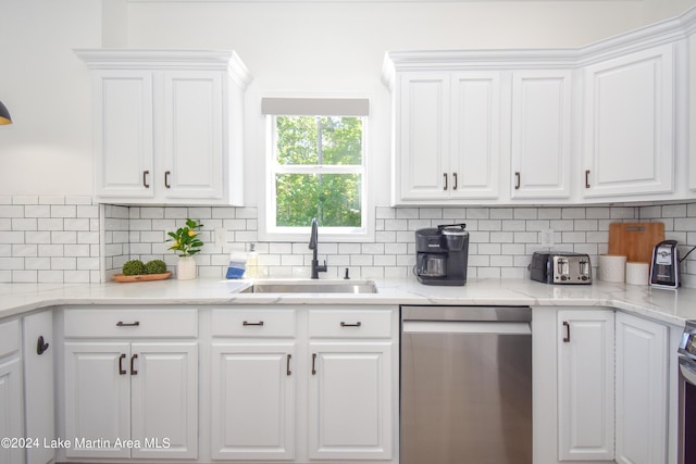 kitchen featuring appliances with stainless steel finishes, white cabinetry, a sink, and tasteful backsplash