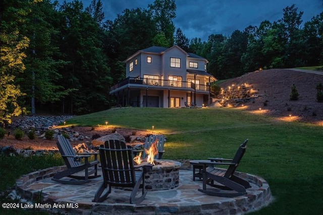 rear view of house featuring an outdoor fire pit, a view of trees, a lawn, a patio, and a deck