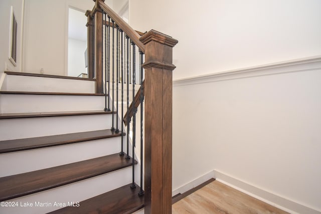 stairway with wood finished floors and baseboards