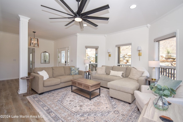 living area featuring ornate columns, crown molding, a wealth of natural light, and wood finished floors