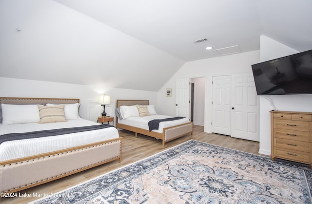 bedroom featuring attic access, lofted ceiling, visible vents, and wood finished floors