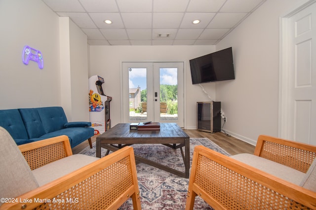 living area featuring french doors, a paneled ceiling, visible vents, wood finished floors, and baseboards