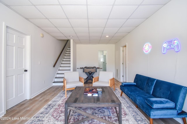 living area with baseboards, visible vents, stairway, wood finished floors, and a paneled ceiling