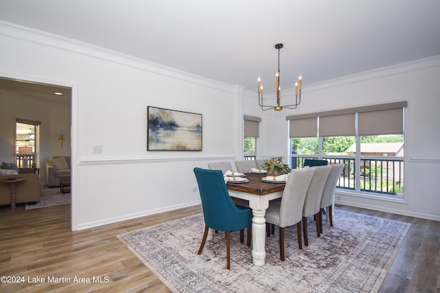 dining space with ornamental molding, wood finished floors, baseboards, and an inviting chandelier