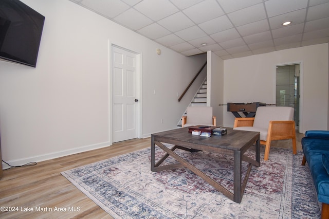 living area with stairway, wood finished floors, a paneled ceiling, and baseboards