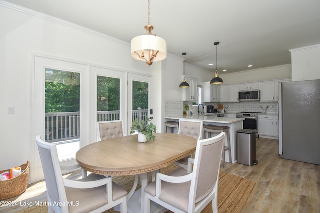 dining area featuring ornamental molding, plenty of natural light, and light wood-style flooring