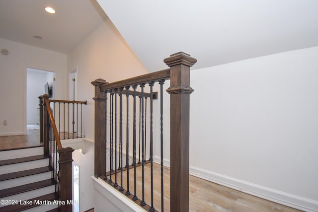 stairs with baseboards, wood finished floors, and recessed lighting