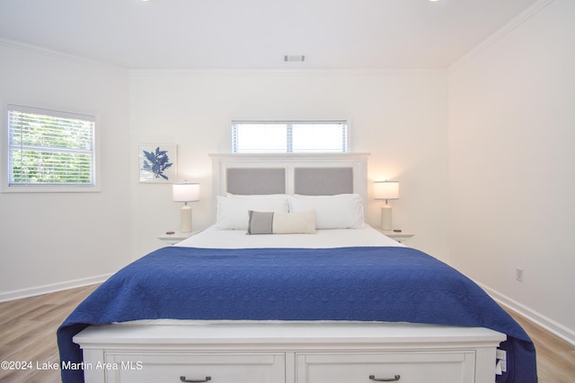 bedroom featuring light wood-style flooring, visible vents, and crown molding