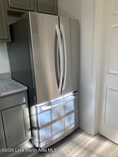 interior details with light hardwood / wood-style floors, light stone counters, and stainless steel refrigerator