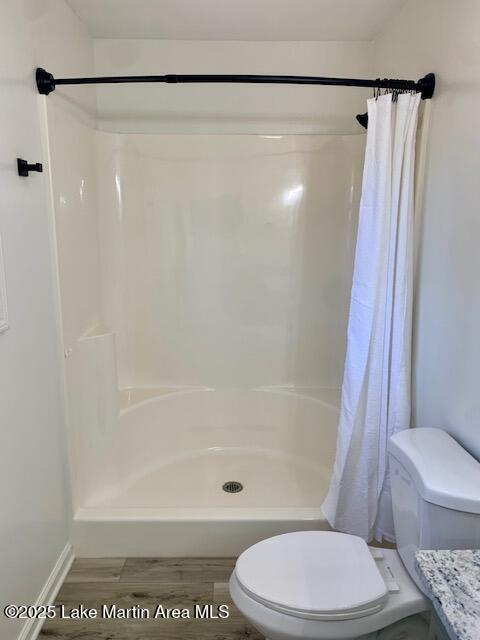 bathroom with hardwood / wood-style flooring, toilet, and a shower with curtain