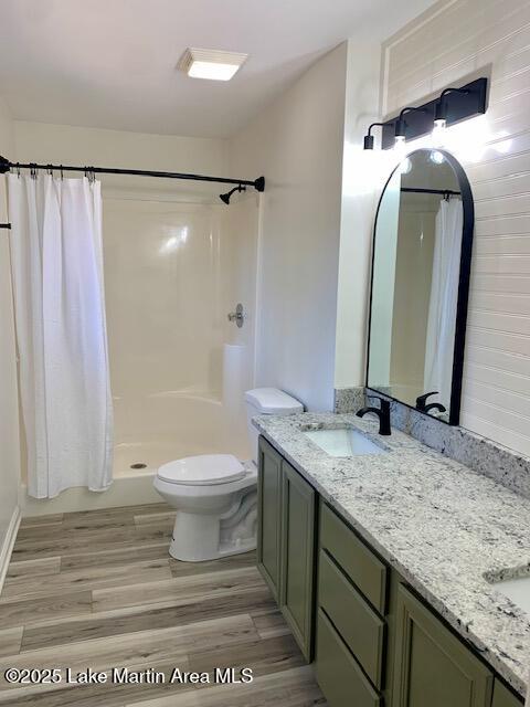 bathroom with hardwood / wood-style flooring, curtained shower, toilet, and vanity