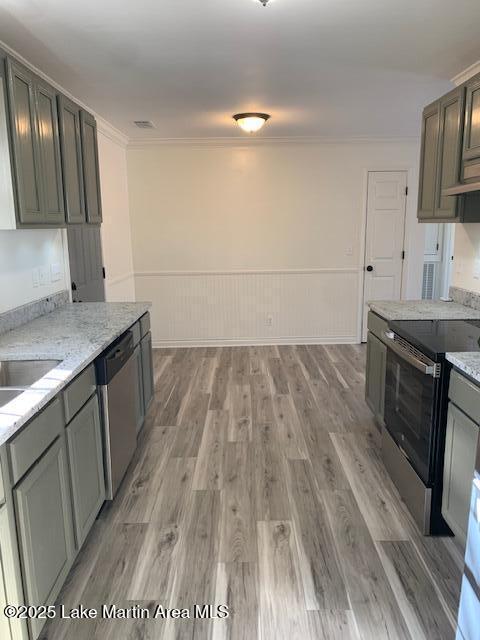 kitchen featuring appliances with stainless steel finishes, crown molding, light hardwood / wood-style flooring, light stone counters, and sink