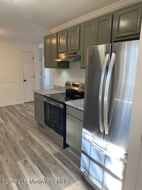 kitchen with light hardwood / wood-style floors, light stone counters, appliances with stainless steel finishes, and ornamental molding