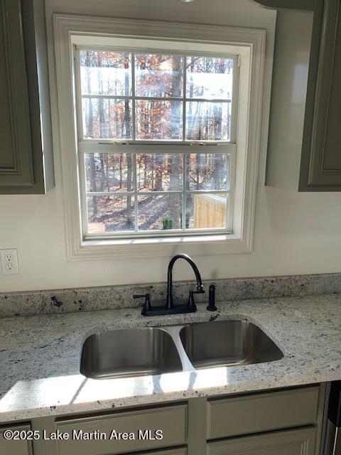 kitchen with light stone countertops, a healthy amount of sunlight, and sink