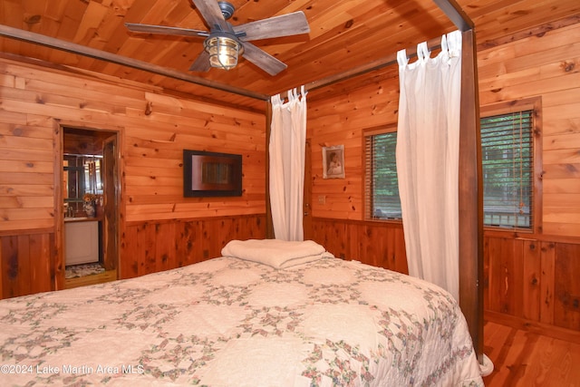 bedroom featuring ceiling fan, wood-type flooring, and wooden walls