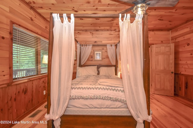 unfurnished bedroom featuring wooden walls, ceiling fan, wood ceiling, and hardwood / wood-style flooring