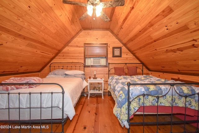 bedroom featuring cooling unit, wooden walls, vaulted ceiling, hardwood / wood-style flooring, and ceiling fan