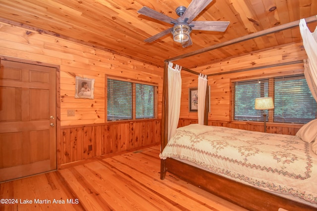 unfurnished bedroom with ceiling fan, wooden ceiling, wooden walls, and light hardwood / wood-style flooring