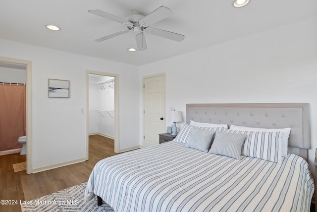 bedroom with hardwood / wood-style floors, ensuite bath, ceiling fan, a spacious closet, and a closet