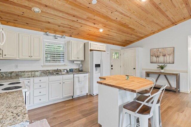 kitchen featuring white appliances, white cabinets, vaulted ceiling, and a kitchen island