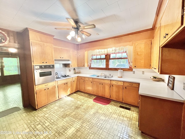 kitchen with ceiling fan, sink, white gas stovetop, crown molding, and oven