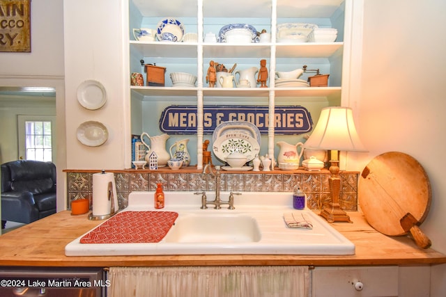 interior details featuring decorative backsplash, dishwasher, and sink