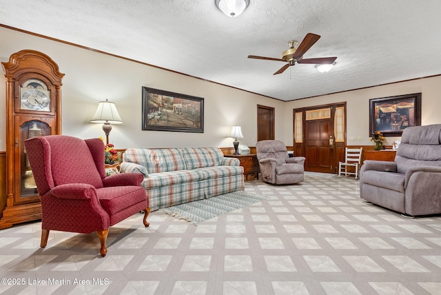 living room with ceiling fan, ornamental molding, and a textured ceiling