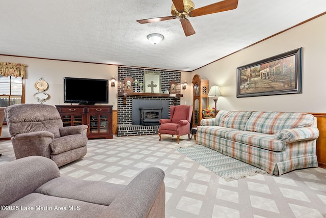 living room featuring ornamental molding, a brick fireplace, ceiling fan, and a textured ceiling