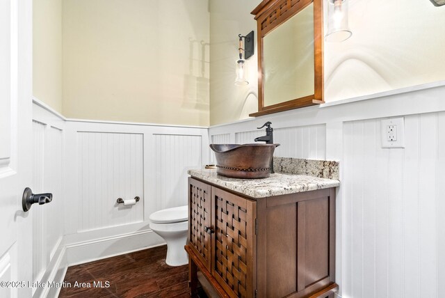 3408 Quail Cv, Opelika, AL 36801 - half bath with toilet, a decorative wall, vanity, wood finished floors, and wainscoting