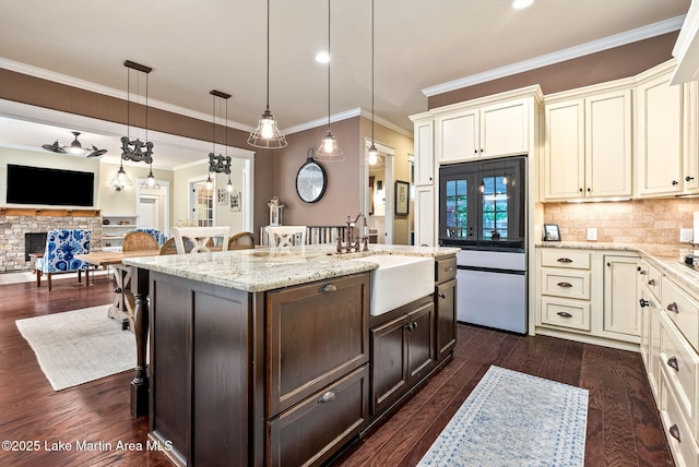 3408 Quail Cv, Opelika, AL 36801 - kitchen featuring a sink, a breakfast bar area, dark brown cabinetry, an island with sink, and cream cabinetry