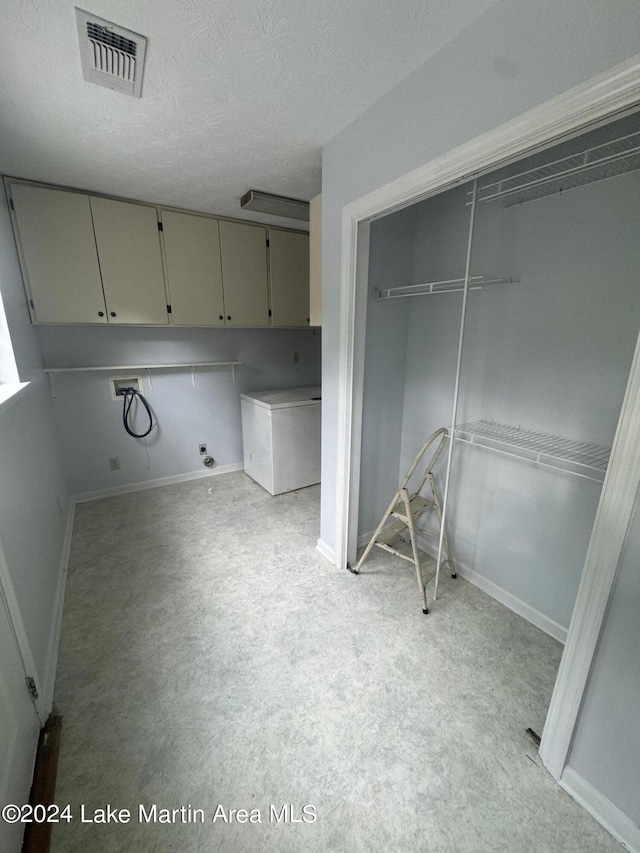 interior space with cabinet space, baseboards, visible vents, a textured ceiling, and washer hookup