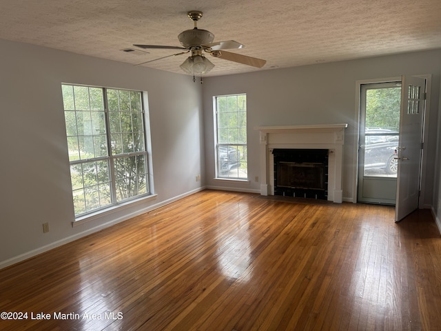 unfurnished living room featuring a textured ceiling, a tiled fireplace, and hardwood / wood-style flooring