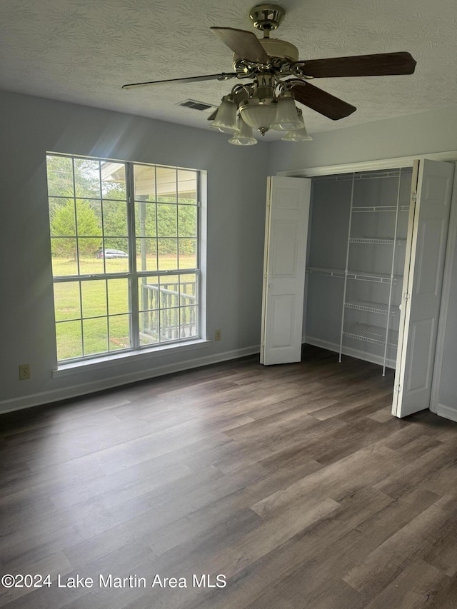 unfurnished bedroom featuring dark wood-style floors, a textured ceiling, a closet, and visible vents