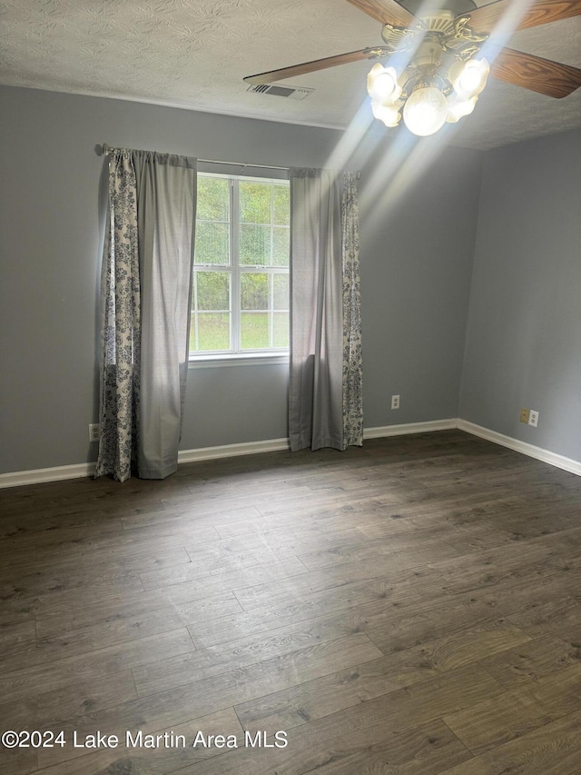 spare room with a ceiling fan, visible vents, and wood finished floors