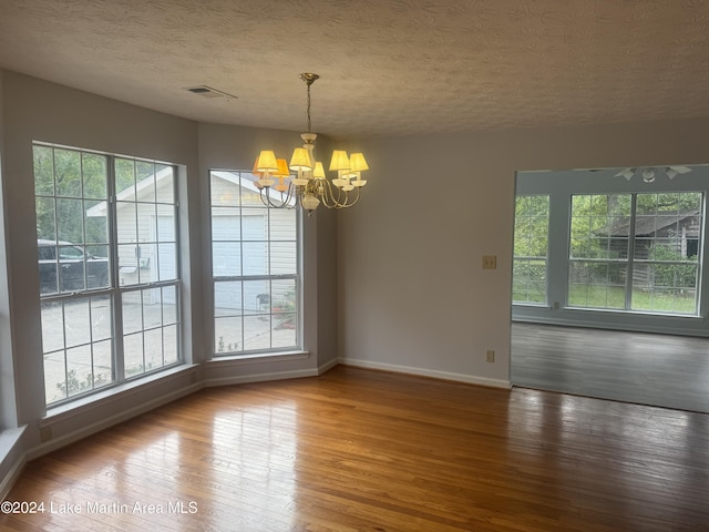 interior space featuring a chandelier, hardwood / wood-style floors, a wealth of natural light, and visible vents