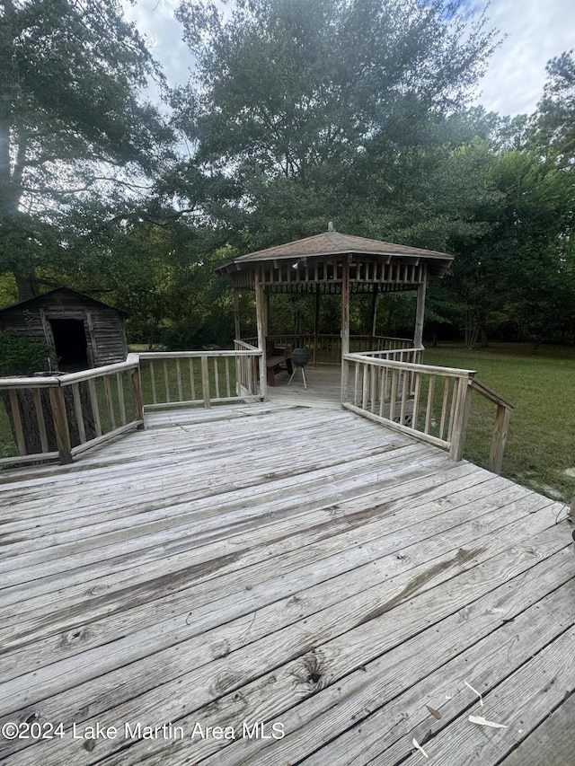 wooden terrace featuring a storage unit, an outbuilding, and a gazebo