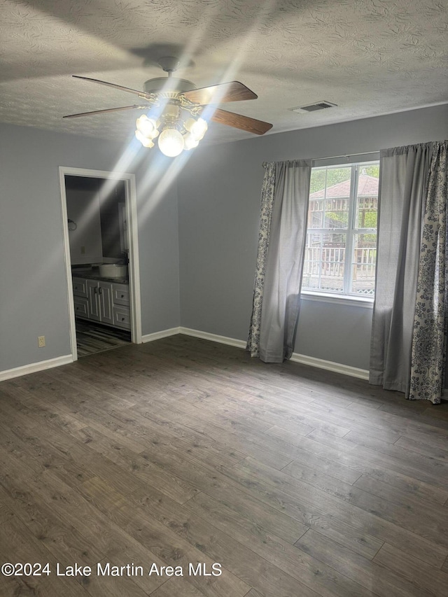 spare room with dark wood-style flooring, visible vents, and baseboards