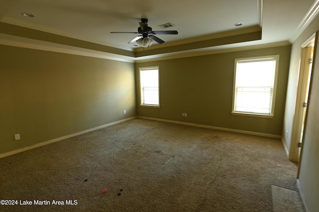 carpeted empty room featuring a tray ceiling, ceiling fan, and crown molding