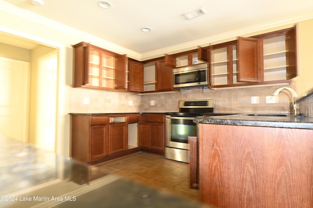 kitchen featuring sink, dark tile patterned floors, ornamental molding, and appliances with stainless steel finishes