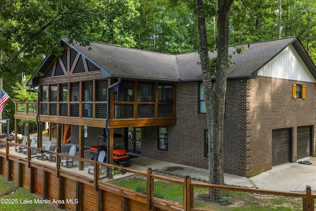 57 Lakeview Pt, Alexander City, AL 35010 - back of house featuring a sunroom, a shingled roof, brick siding, concrete driveway, and a patio area