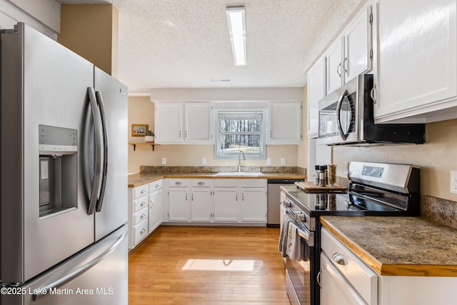 57 Lakeview Pt, Alexander City, AL 35010 - kitchen with stainless steel appliances, light wood finished floors, white cabinetry, and a textured ceiling