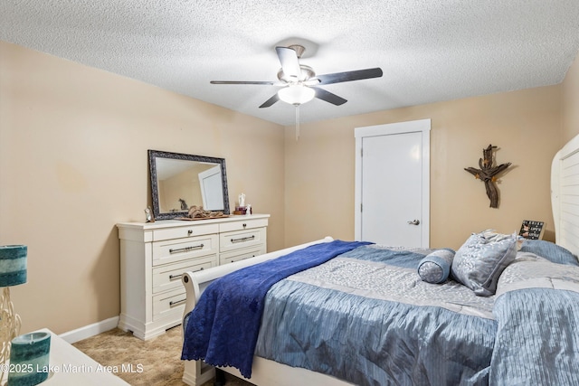 bedroom with light carpet, a ceiling fan, baseboards, and a textured ceiling