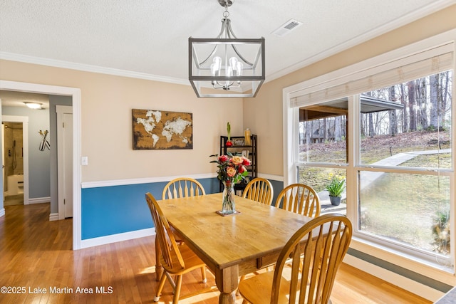 dining room featuring ornamental molding, light wood-type flooring, and a wealth of natural light