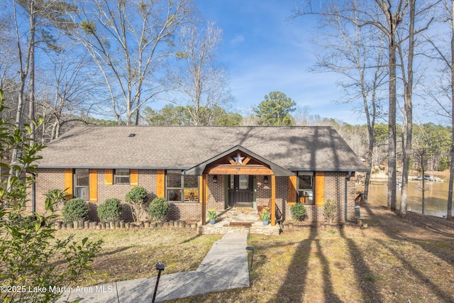 view of front of house with brick siding and roof with shingles