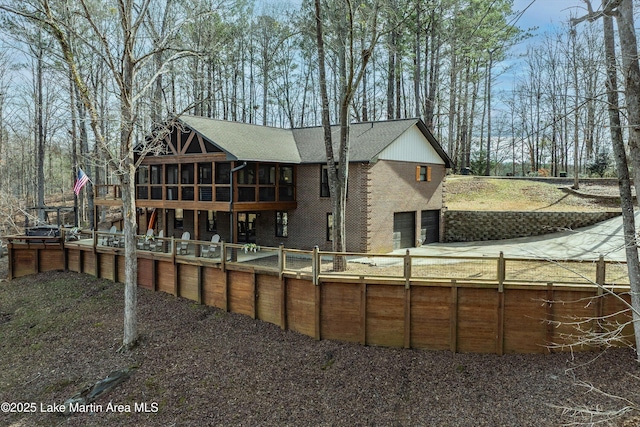 back of property with a garage, a sunroom, and brick siding